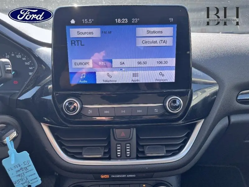 Tableau de bord de Ford Fiesta 2022 avec écran tactile affichant la radio RTL, entouré de commandes noires brillantes.