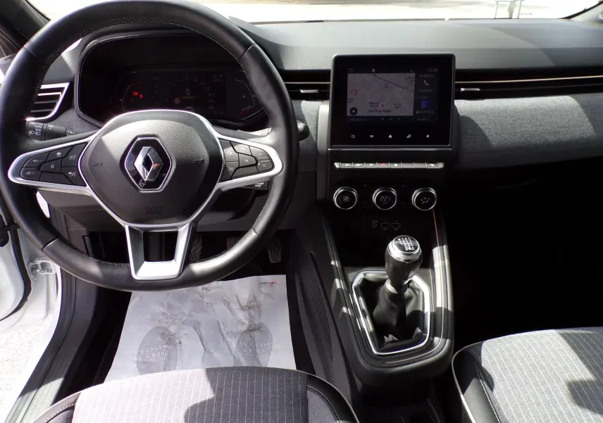 Intérieur de la Renault Clio V blanche 2022, vue frontale sur le volant multifonction et la console avec boîte manuelle.