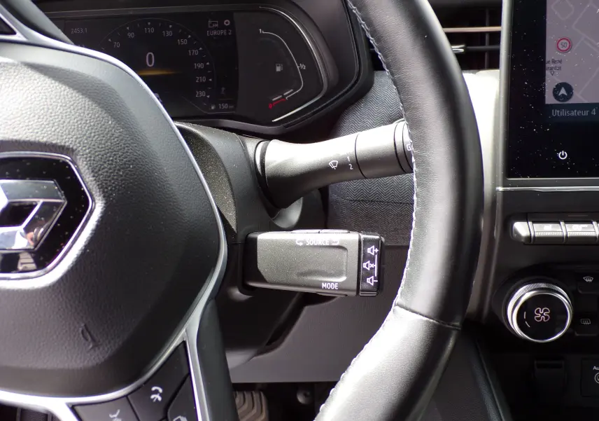 Vue rapprochée du volant noir de la Renault Clio V 1.3 TCE 140 ch avec commandes et tableau de bord numérique.