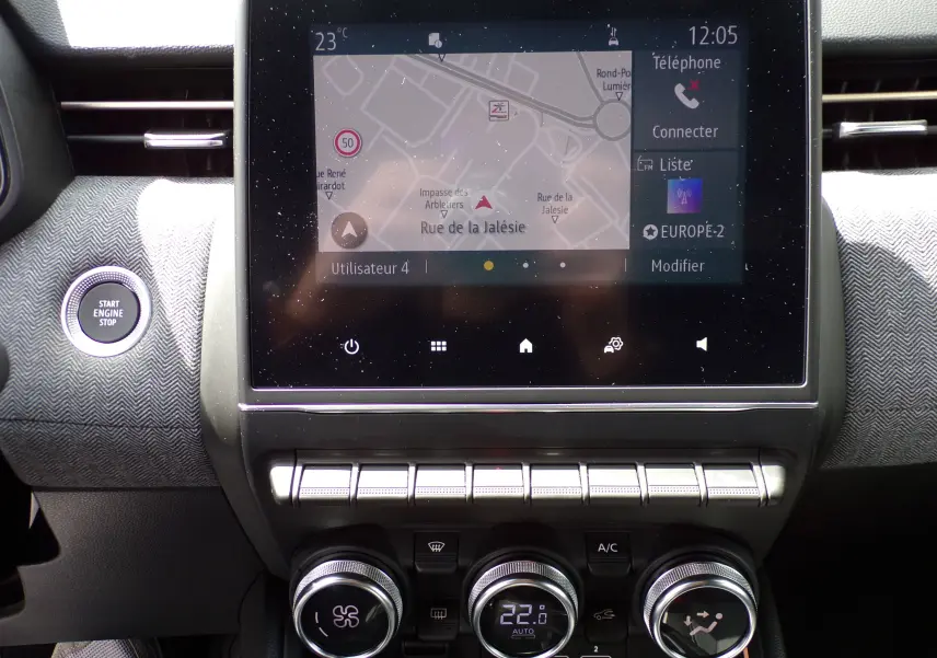 Tableau de bord de Renault Clio V blanc 2022, vue centrée sur l'écran tactile et les commandes de climatisation.