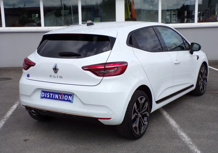 Renault Clio V blanche vue en 3/4 arrière droit, avec vitres teintées et jantes alliage bicolores.