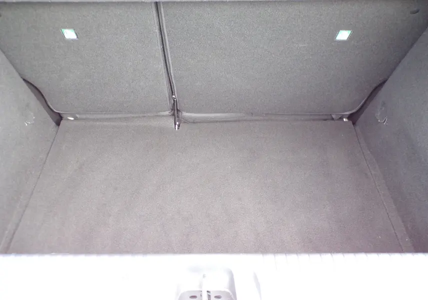 Coffre vide de la Renault Clio V blanche, vue plongeante sur l'espace de chargement intérieur.