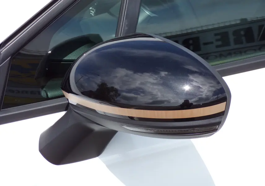 Rétroviseur côté gauche noir brillant avec bande beige sur Renault Clio V blanche essence 2022, vue rapprochée.