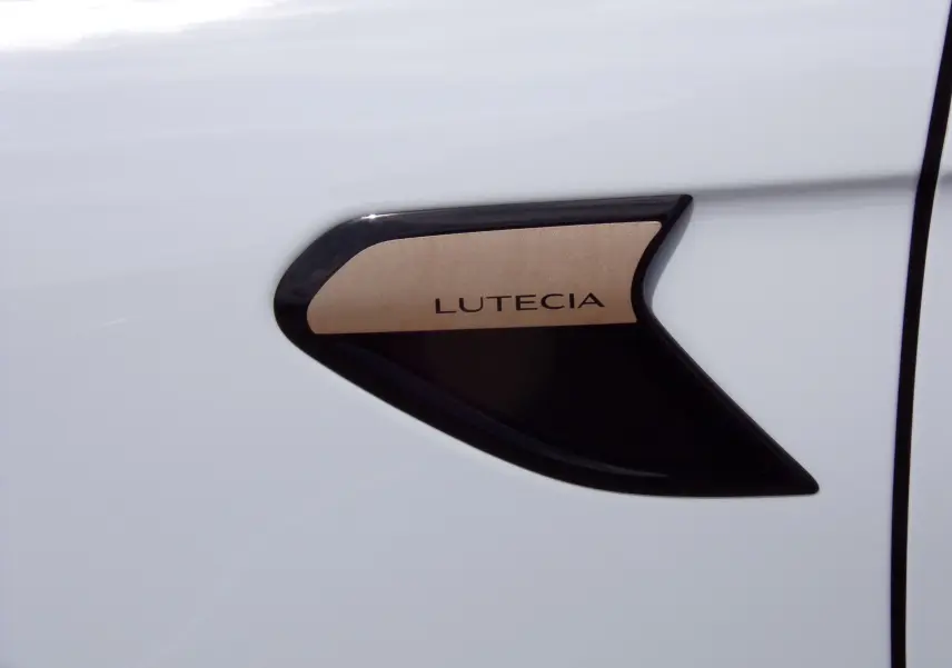 Détail de l'écusson LUTECIA noir et doré sur la porte blanche d'une Renault Clio V 2022.