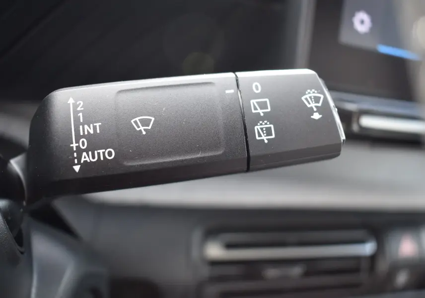 Gros plan sur la commande des essuie-glaces du Citroën C3 2025 avec indications blanches sur fond noir à l'intérieur du véhicule.