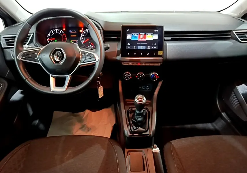 Vue intérieure centrée sur le tableau de bord et volant cuir de la Renault Clio 2023, avec écran tactile et boîte manuelle.