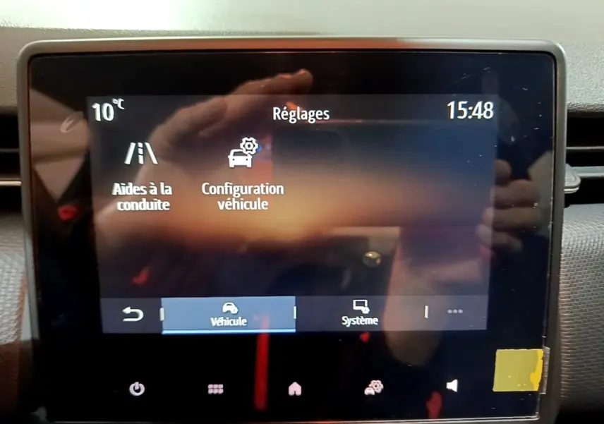 Écran tactile central de la Renault Clio gris clair 2023 affichant les réglages d’aides à la conduite et configuration véhicule.