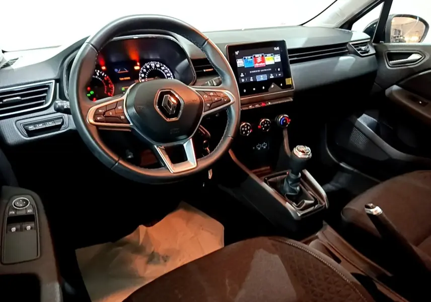 Vue intérieure côté conducteur de la Renault Clio gris clair 2023, volant cuir multifonctions et écran tactile central.
