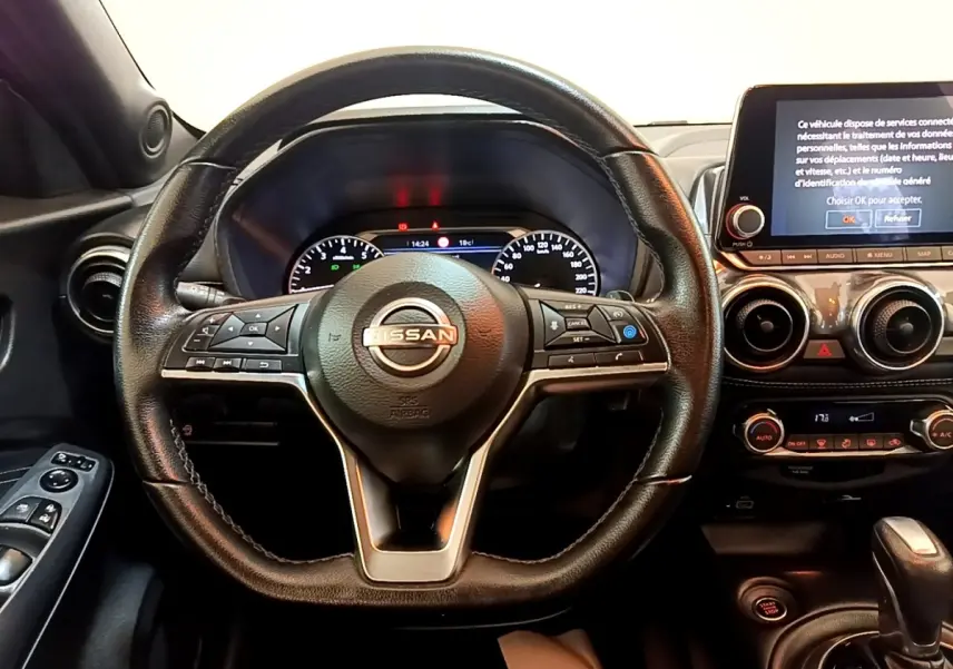 Vue intérieure centrée sur le volant Nissan Juke noir 2022 avec tableau de bord digital et écran tactile.