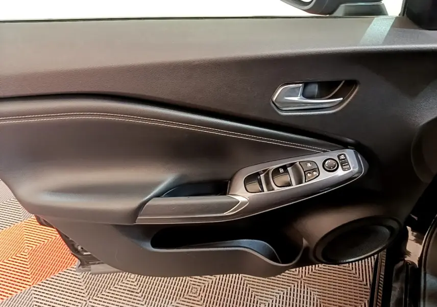 Vue rapprochée de la porte avant gauche noire du Nissan Juke 2022, avec commandes électriques et poignée argentée.