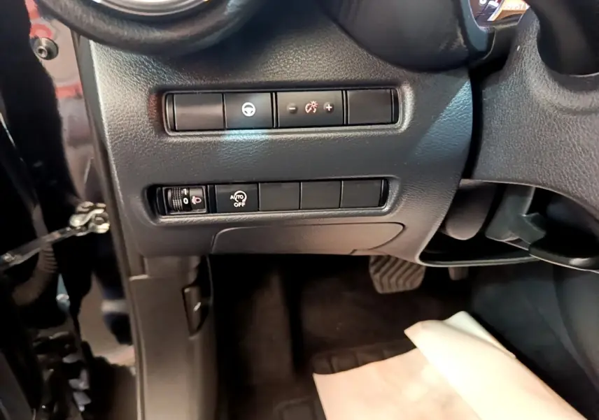 Vue intérieure côté conducteur du tableau de bord noir avec commandes d’éclairage et réglage du volant d’un Nissan Juke 2022.