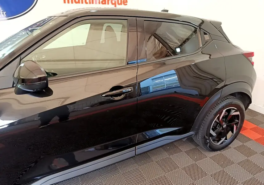 Vue latérale côté droit du Nissan Juke noir 2022 avec jantes noires et rétroviseurs ton caisse.