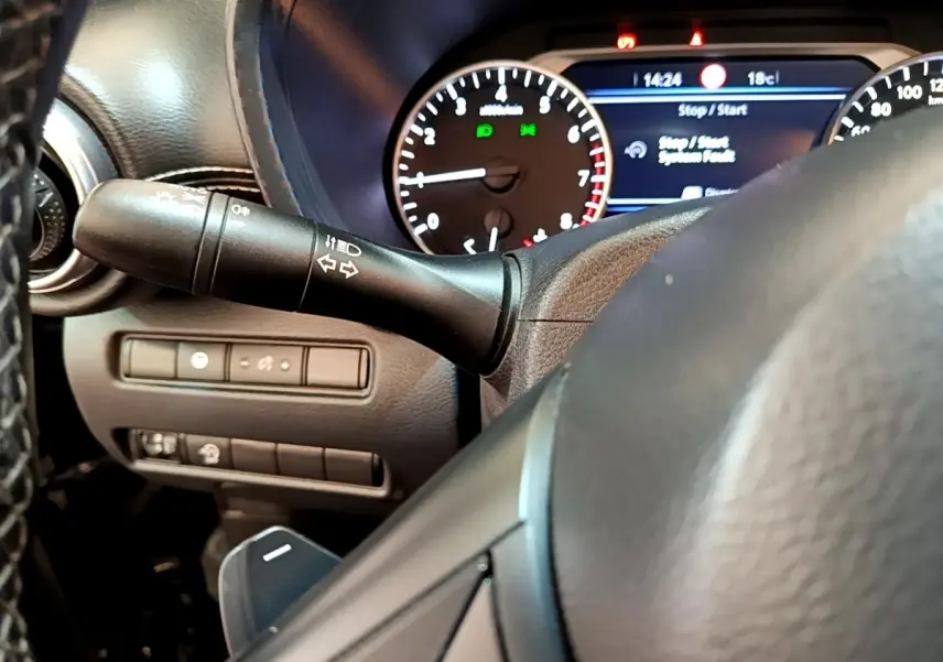 Gros plan sur le volant et le combiné d'instruments numérique du Nissan Juke noir, affichage multifonctions visible.