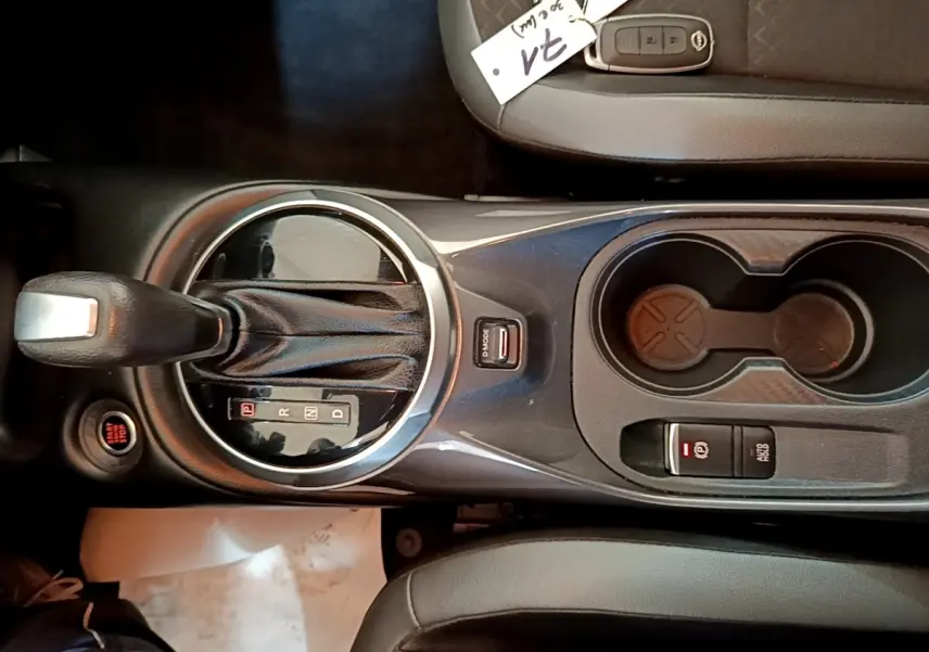 Vue plongeante sur la console centrale noire du Nissan Juke 2022, avec levier de boîte auto et porte-gobelets.