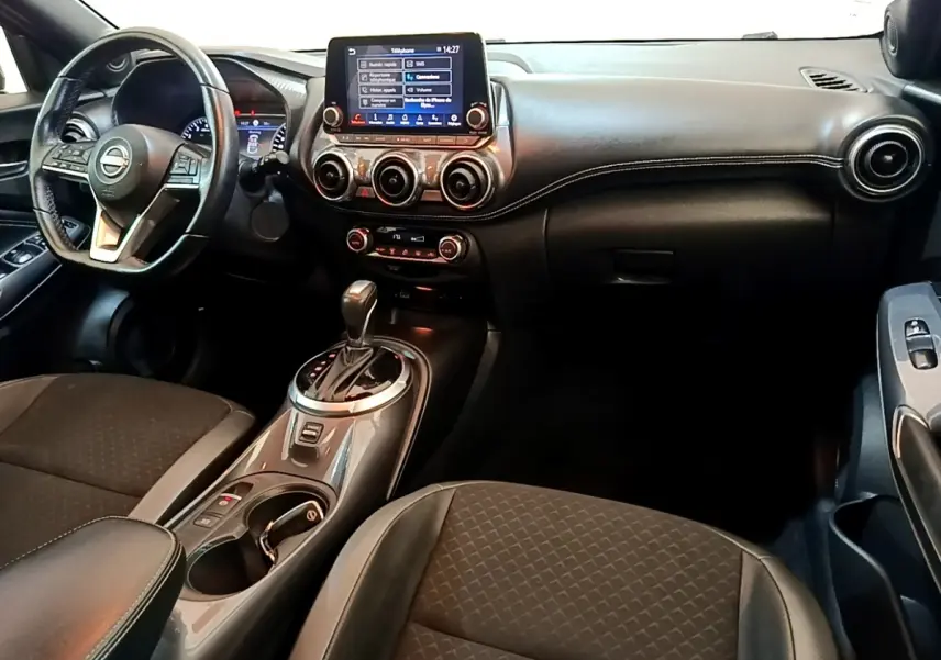 Vue intérieure avant du Nissan Juke 2022 noir, tableau de bord avec écran tactile central et volant multifonctions.