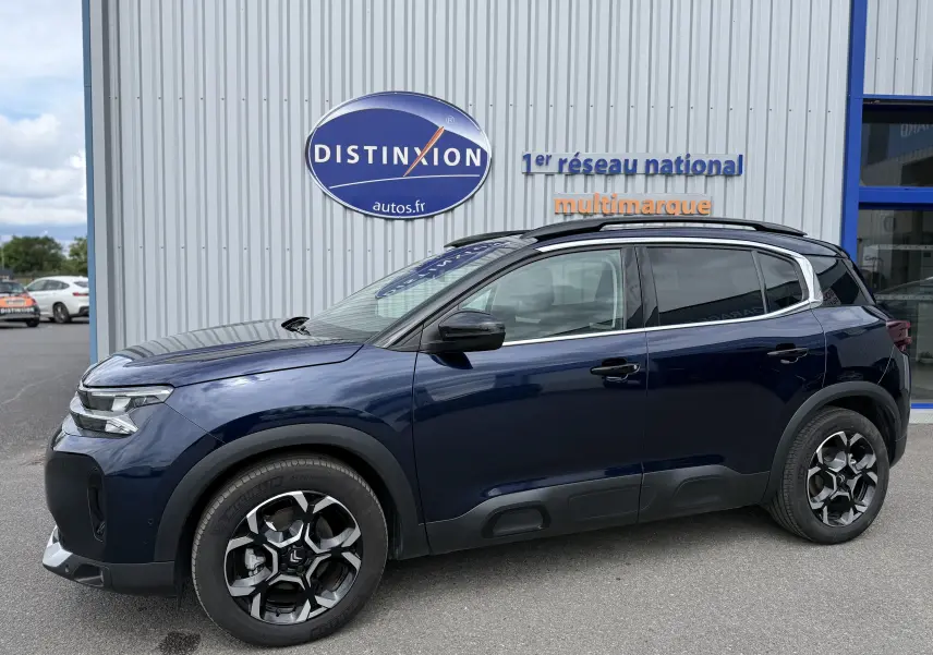 Vue de profil côté gauche d’un Citroën C5 Aircross Hybrid 145 bleu foncé avec jantes bi-ton et protections noires sur les bas de caisse.