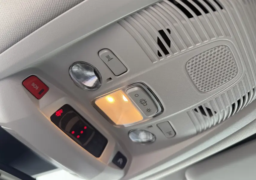 Vue en gros plan du plafonnier intérieur gris clair du Citroën C5 Aircross Hybrid 2025 avec éclairage et boutons SOS et assistance.