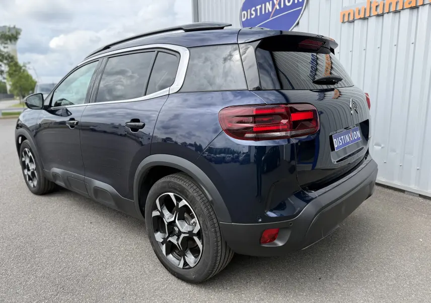 Vue 3/4 arrière droite d’un Citroën C5 Aircross Hybrid 145 e-DSC6 Max bleu foncé avec jantes noires et toit noir.