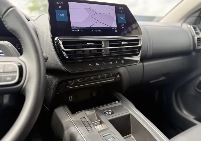 Vue intérieure côté conducteur du tableau de bord et console centrale du Citroën C5 Aircross Hybrid bleu foncé avec écran tactile et commandes modernes.