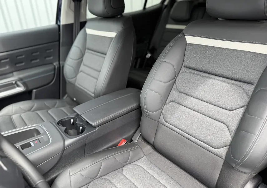 Vue intérieure rapprochée des sièges avant gris et noir du Citroën C5 Aircross Hybrid 145 e-DSC6 Max avec accoudoir central.