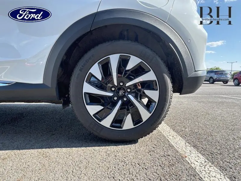 Gros plan sur la roue arrière droite du Ford Puma blanc Glacier 2024 avec jante noire et argentée au design moderne.