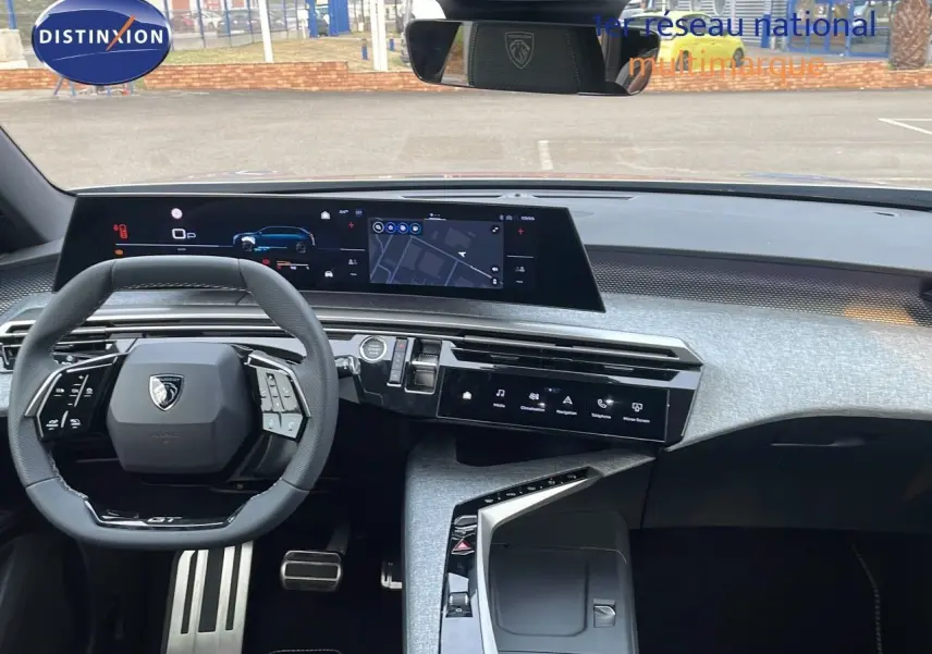 Intérieur moderne du Peugeot 5008 Hybrid 136ch GT 2025, vue du tableau de bord avec écran large et volant compact noir.