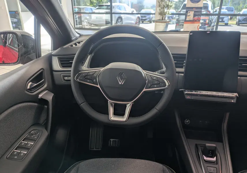 Vue intérieure centrée sur le volant Renault Captur 2025, tableau de bord moderne avec écran tactile vertical noir.