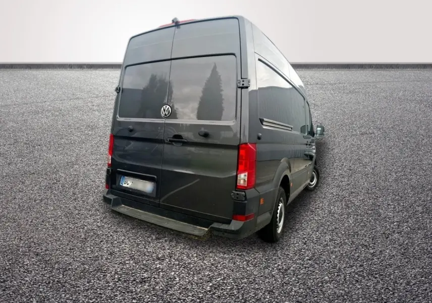 Volkswagen Crafter gris foncé vu en 3/4 arrière droit, fourgon avec portes arrière pleines et feux rouges visibles.