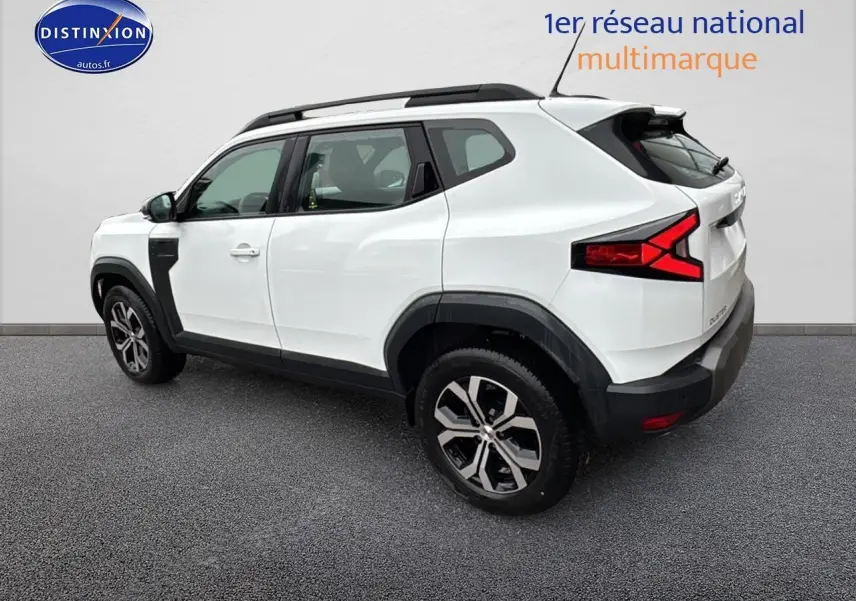 Vue 3/4 arrière droite du Dacia Duster blanc Arctic avec barres de toit et jantes alliage noires.