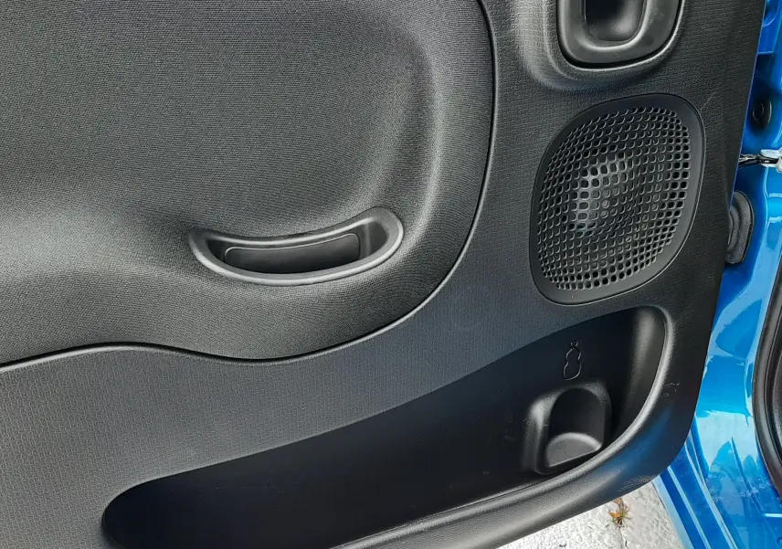 Gros plan sur la porte avant droite noire de la Fiat Panda Bleu Italia avec haut-parleur et poignée intégrée.