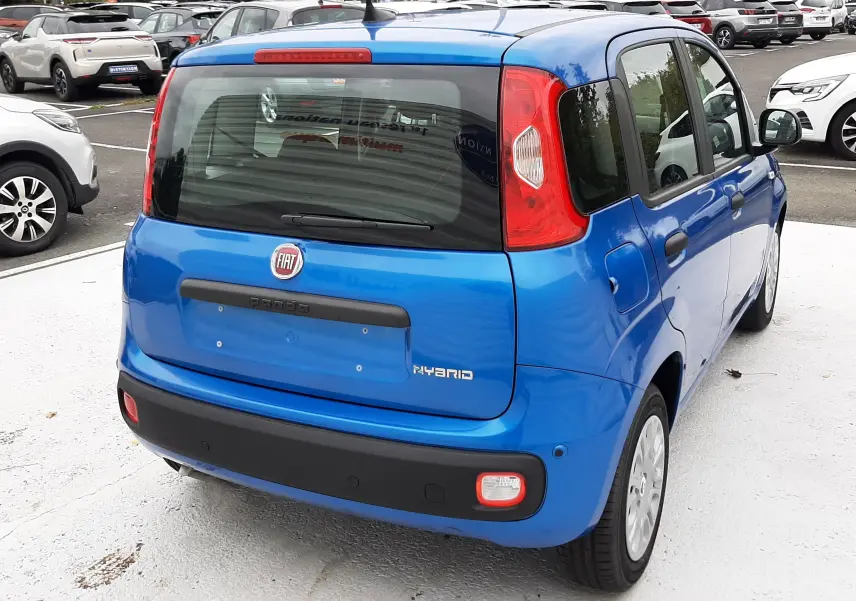 Vue 3/4 arrière droite d'une FIAT Panda 2025 bleu Italia avec logo hybride et hayon fermé sur parking extérieur.