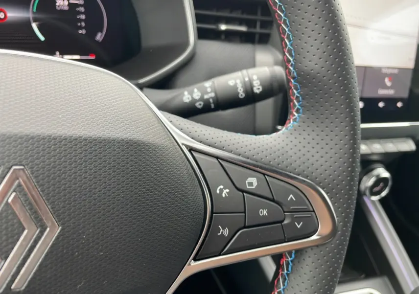 Gros plan sur le volant perforé avec surpiqûres tricolores de la Renault Clio V E-Tech 145 Esprit Alpine 2025.
