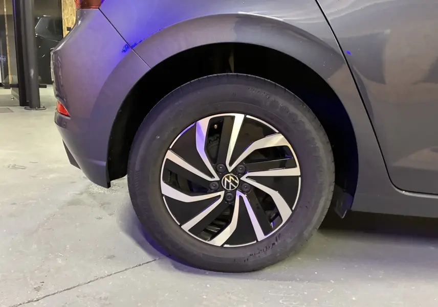 Gros plan sur la roue arrière gauche d'une Volkswagen Polo gris métallisé avec jante alliage bicolore moderne.