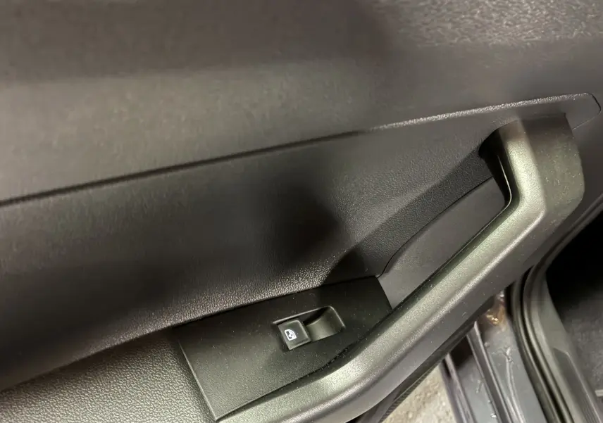 Poignée intérieure et bouton de commande de vitre électrique sur la porte côté droit d'une Volkswagen Polo grise 2025.