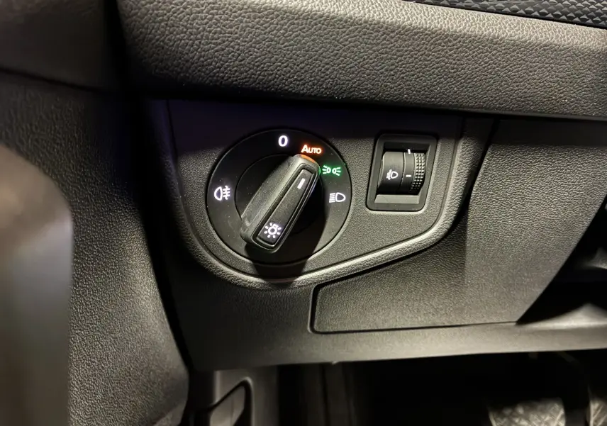 Gros plan sur le bouton de commande des phares et réglage de l'éclairage intérieur dans une Volkswagen Polo gris 2025.