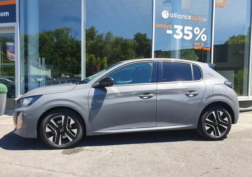 Profil côté gauche d'une Peugeot 208 gris Sellenium 2025 avec jantes alliage bi-tons devant une vitrine.