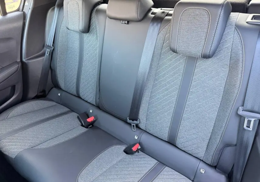 Vue rapprochée de la banquette arrière grise tissu et cuir de la Peugeot 208 1.2 100ch Allure, avec appuie-têtes et ceintures visibles.
