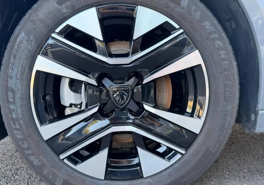 Gros plan sur la jante alu bicolore noire et argentée avec logo Peugeot au centre, montée sur pneu Michelin.