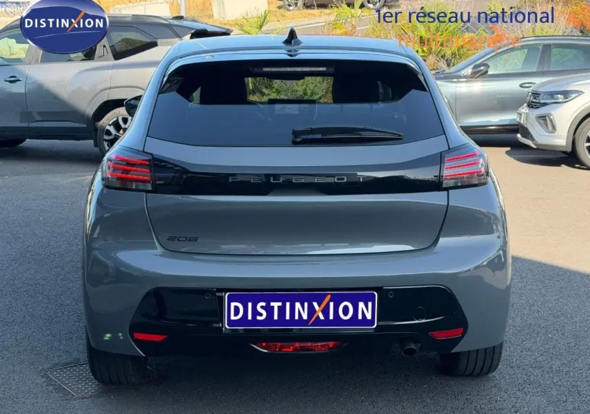 Vue arrière d'une Peugeot 208 grise garée, avec feux arrière LED et lunette arrière surteintée.