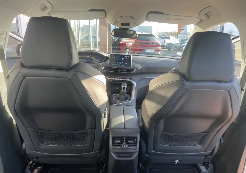 Vue intérieure arrière du Peugeot 3008 blanc nacré 2019, montrant les sièges avant en cuir noir et la console centrale avec écran tactile.