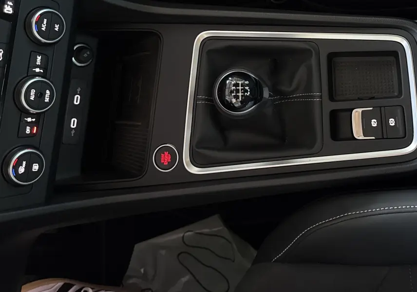 Gros plan sur la console centrale noire du SEAT Ateca 2024 avec levier de vitesse manuel et bouton start/stop rouge.