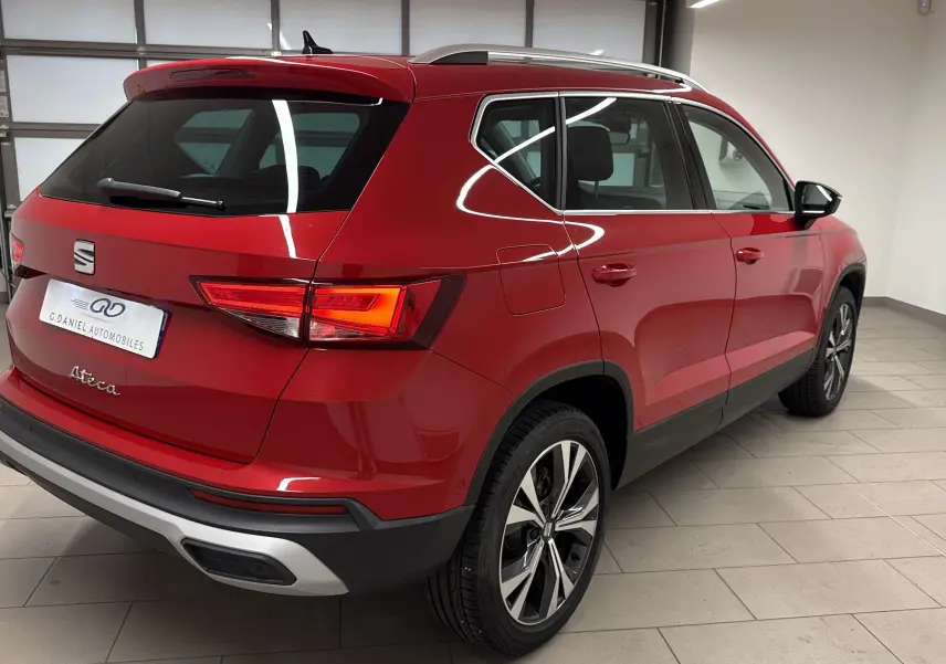 Vue 3/4 arrière droite du SUV SEAT Ateca Rouge Velvet 2024 avec jantes alliage et feux allumés.