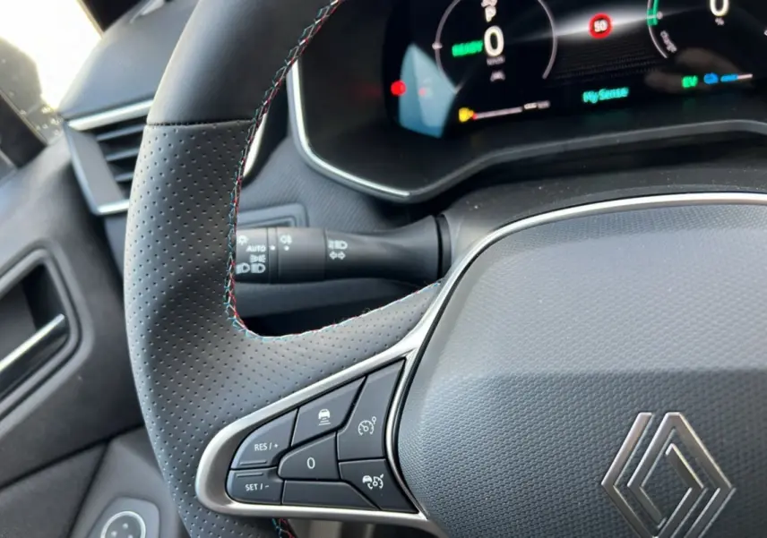 Intérieur de la Renault Clio V E-Tech 145 Esprit Alpine 2025, volant noir perforé avec coutures tricolores et tableau de bord numérique.