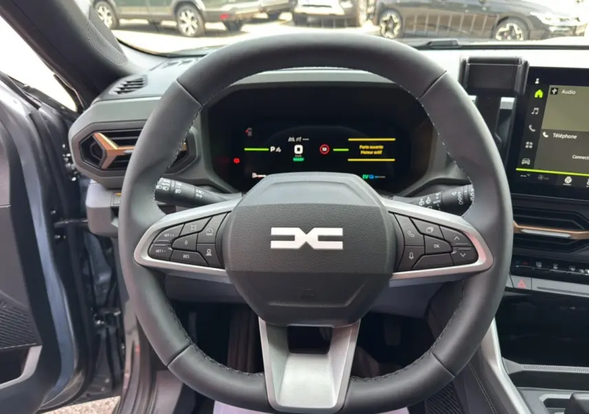 Vue intérieure centrée sur le volant cuir noir du Dacia Bigster Hybrid 155 Extreme Plus gris schiste avec tableau de bord digital.