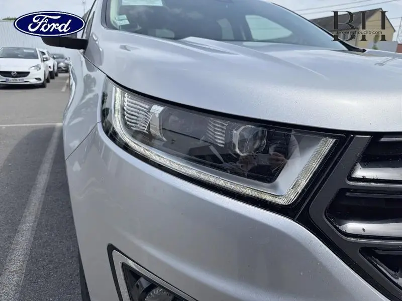 Gros plan sur le phare avant droit gris Ingot du Ford Edge 2016 avec calandre noire et feux LED distinctifs.