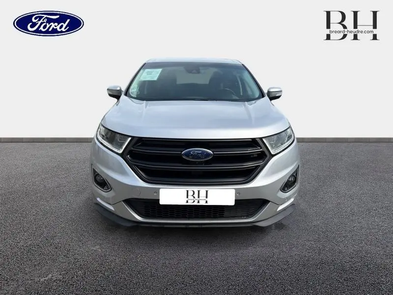 Vue de face d'un Ford Edge gris Ingot 2016 avec calandre noire et phares LED dynamiques allumés.