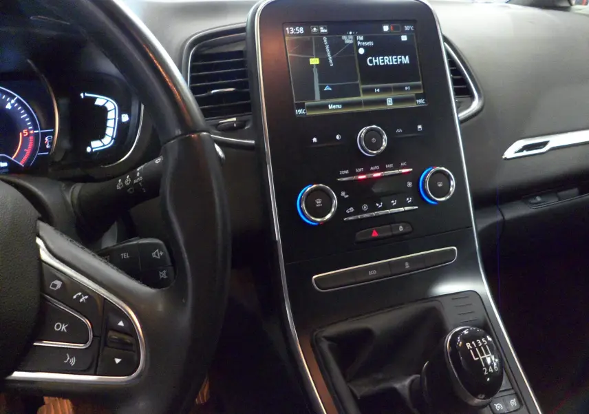 Vue intérieure du tableau de bord et levier de vitesses manuel du Renault Grand Scenic IV blanc glacier, avec écran tactile allumé.