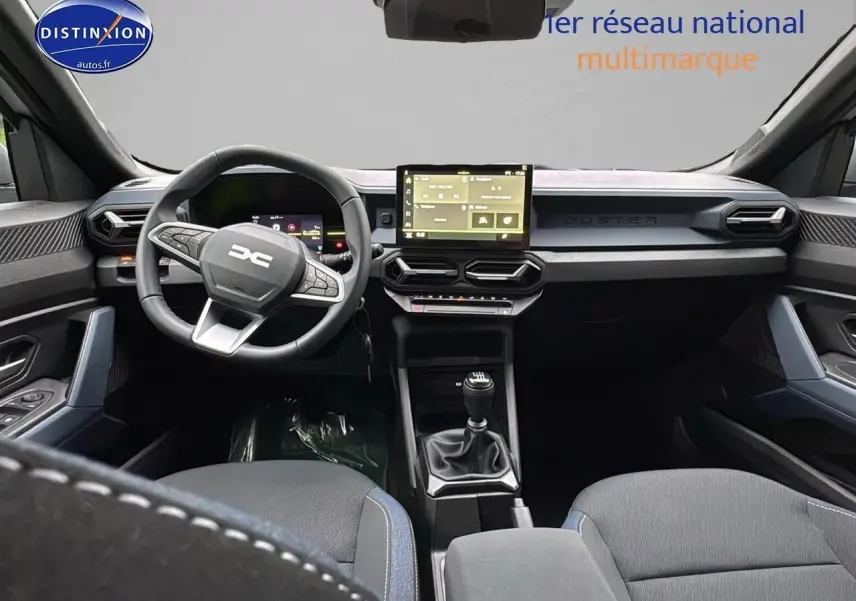 Intérieur du Dacia Duster 2025 vu de face, tableau de bord moderne avec écran tactile et volant multifonction noir.