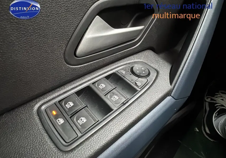 Gros plan sur les commandes des vitres électriques côté conducteur du Dacia Duster blanc Arctic 2025.