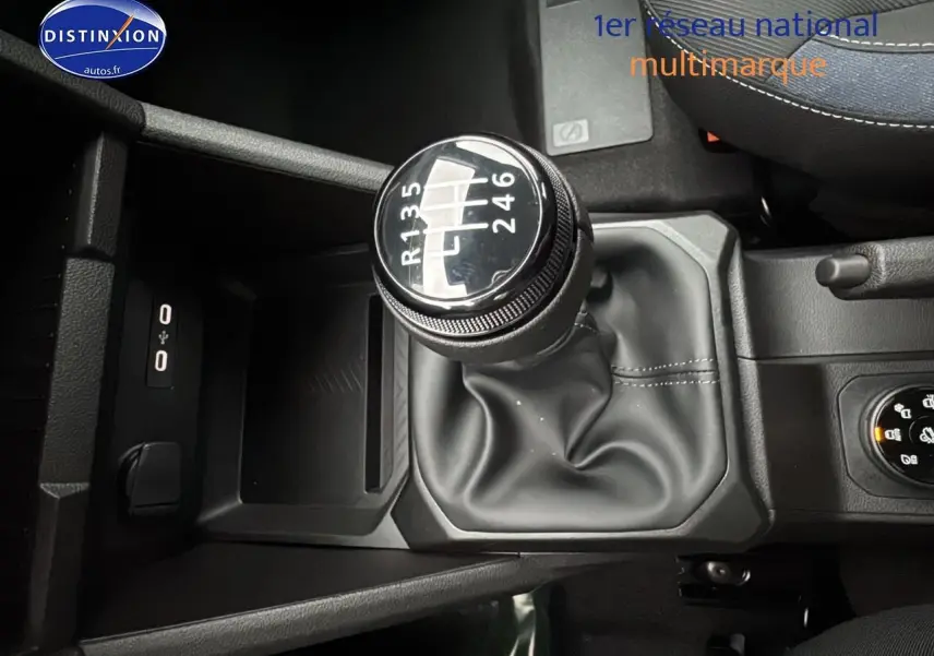 Gros plan sur le levier de vitesses manuel noir du Dacia Duster blanc Arctic, avec console centrale et accoudoir visible.